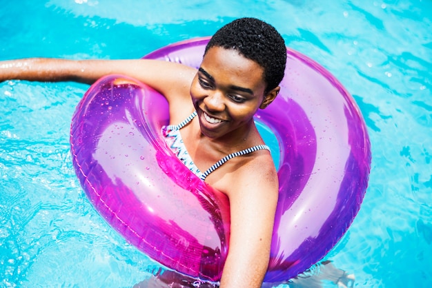 Gros plan d&#39;une femme noire flottant avec un tube dans la piscine