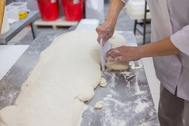 Gros plan de femme pétrir la pâte à pizza.