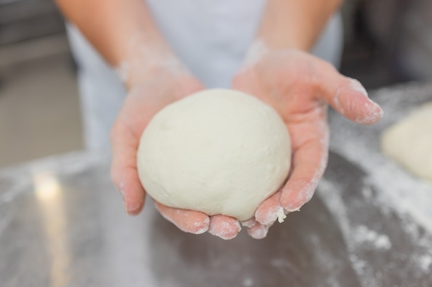 Gros plan de femme pétrir la pâte à pizza.