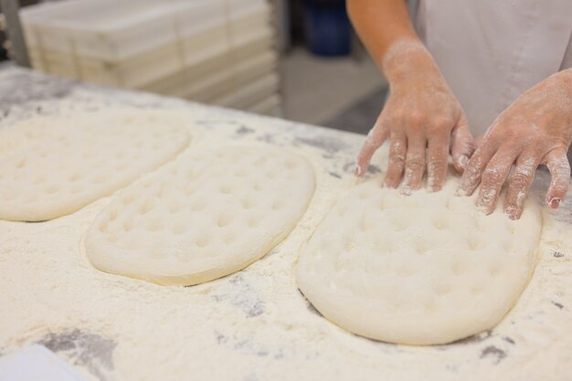 Gros plan de femme pétrir la pâte à pizza.