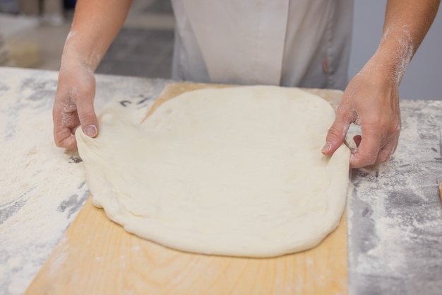 Gros plan de femme pétrir la pâte à pizza.