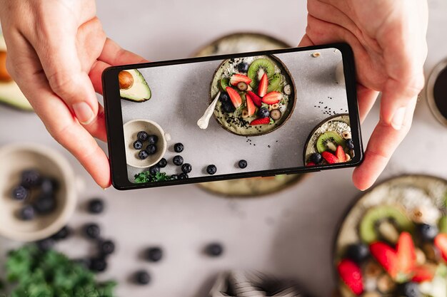 Photo un gros plan d'une femme photographiant des bols de smoothie aux fruits sains