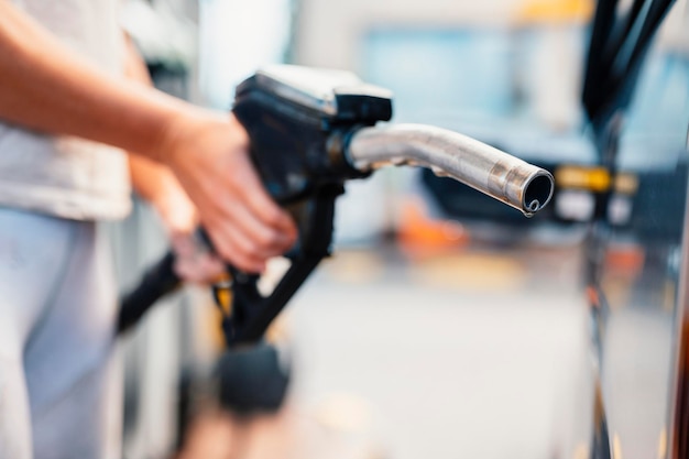 Photo gros plan d'une femme pompant de l'essence dans une voiture à une station-service essence ou essence pompée dans un concept de transport à moteur