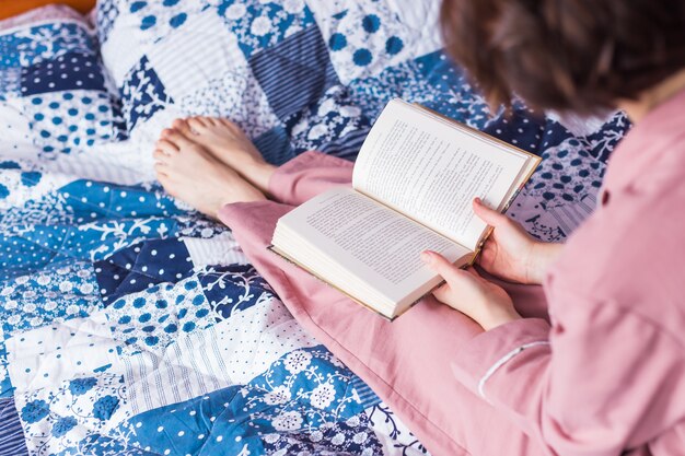 Gros plan d'une femme porte un pyjama et se détendre à la maison et lire un livre.