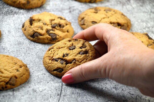 Photo gros plan d'une femme prenant un délicieux biscuit aux pépites de chocolat fraîchement sorti du four