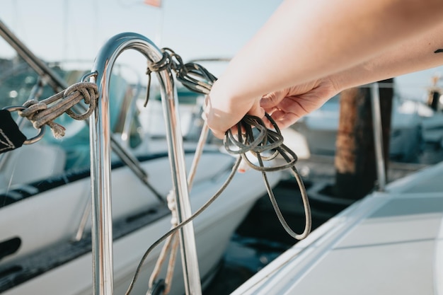 Gros plan femme préparant avec ses mains un noeud et une proue du bateau Fabrication d'un noeud nautique sur son yacht se préparant à naviguer tout en voyageant en mer méditerranée Voyages de luxe