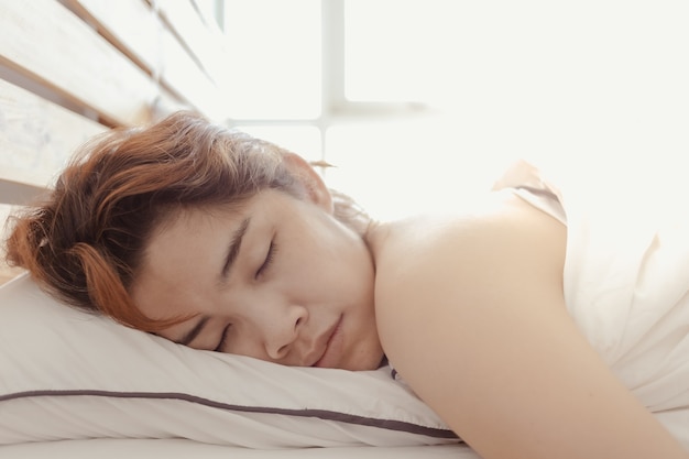 Gros plan d'une femme qui dort sur son lit blanc concept de somnolent