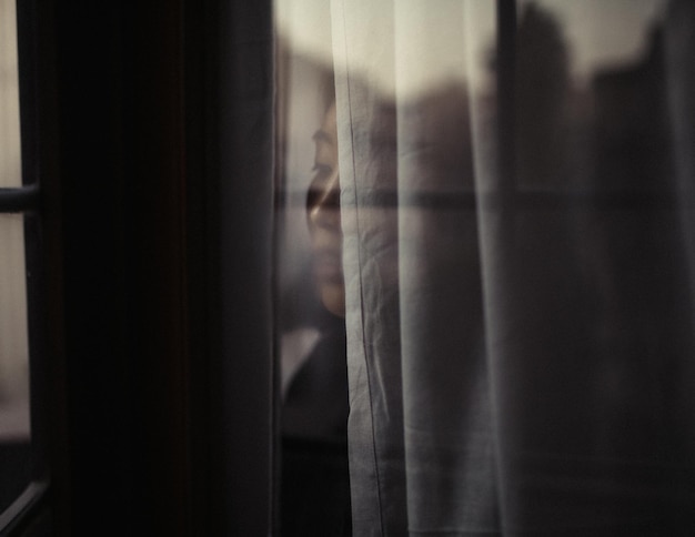 Un gros plan d'une femme qui regarde par la fenêtre.