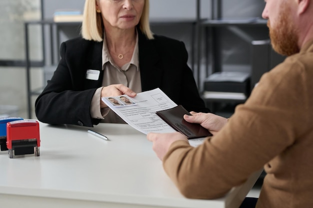 Gros plan sur une femme qui remet un formulaire de demande à un homme qui demande des services gouvernementaux