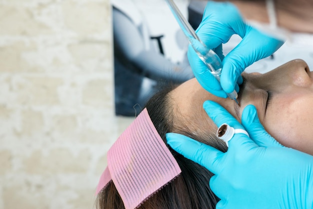 Un gros plan d'une femme qui se fait tatouer un sourcil