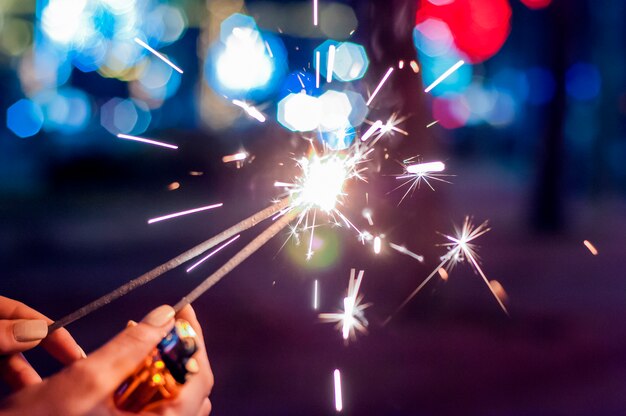 Gros plan d&#39;une femme qui tient des étincelles la nuit. Gros plan, femme, tenue, sparkler, rue