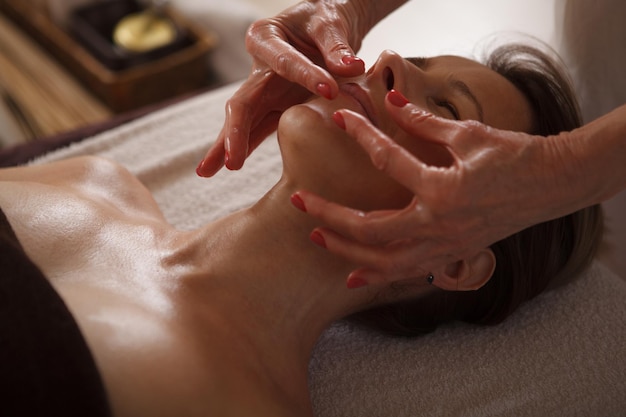 Gros plan d'une femme recevant un massage facial professionnel par un thérapeute de spa