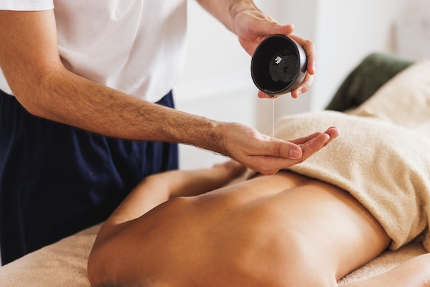 Gros plan d'une femme recevant un massage relaxant à l'huile essentielle au spa.