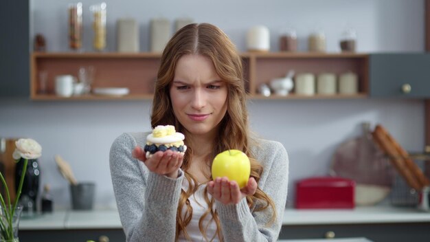 Gros plan femme réfléchie regardant un dessert crémeux et une pomme fraîche dans la cuisine