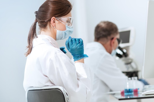 Gros plan femme scientifique assise à une table de laboratoire