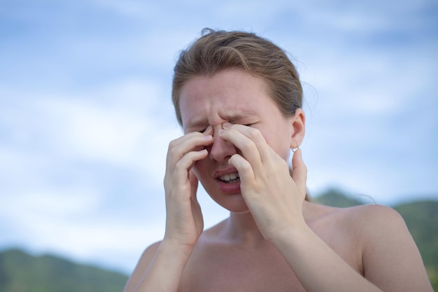 Gros plan d'une femme se grattant les démangeaisons et se frottant les yeux avec ses mains dans un parc problèmes d'allergie visuelle