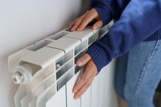 Gros plan d'une femme se réchauffant les mains sur le radiateur à la maison pendant les froides journées d'hiver Saison de chauffage