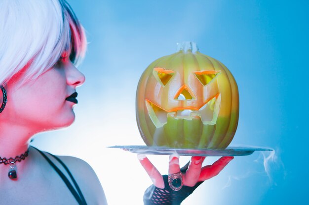 Gros plan d'une femme sexy avec une citrouille d'halloween effrayante
