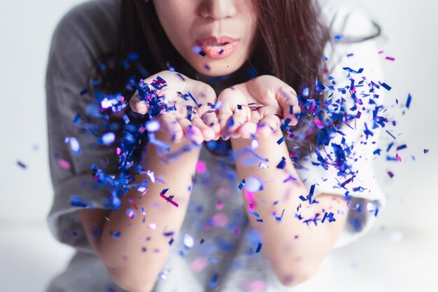 Photo un gros plan d'une femme soufflant des confettis