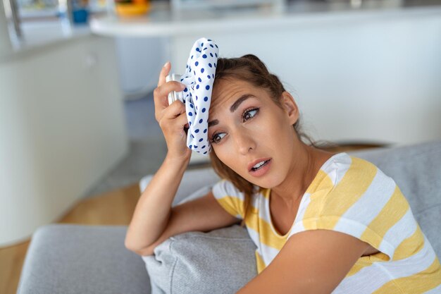 Gros plan d'une femme souffrant d'un mal de tête refroidissant sa tête avec un sac de glace