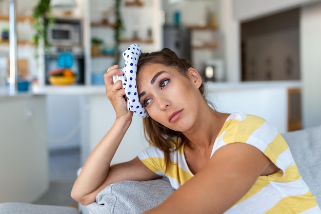 Gros plan d'une femme souffrant d'un mal de tête refroidissant sa tête avec un sac de glace