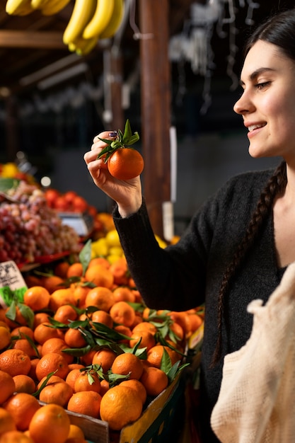 Gros plan femme souriante achetant de la mandarine