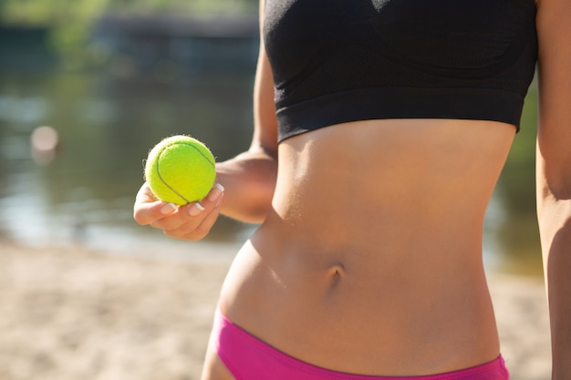 Gros plan d'une femme sportive avec un corps parfait tenant une balle de tennis. Espace libre