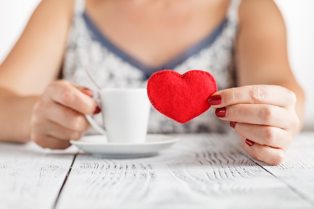 Gros plan de femme tenant un café avec le symbole du coeur