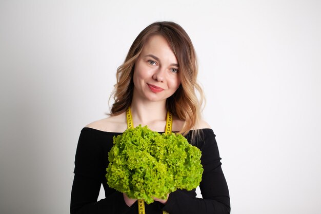 Gros plan d'une femme tenant du brocoli avec du ruban adhésif pour mesurer.