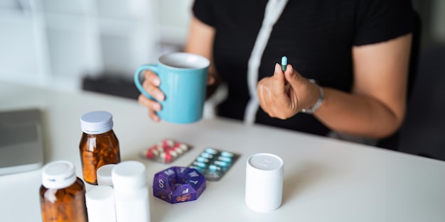 En gros plan, une femme tenant une pilule à la main avec de l'eau se sent malade. Une femme va prendre un analgésique contre les maux de tête. Un analgémicien.