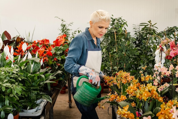 Photo gros plan sur une femme tenant un pot arrosant une plante verte à la maison