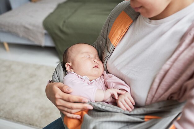 Gros plan d'une femme tenant son bébé endormi sur les mains couvrant avec une couverture