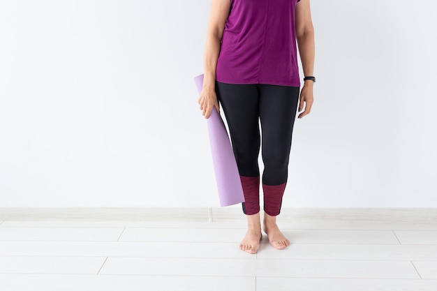 Gros plan d'une femme tenant un tapis après un cours de yoga