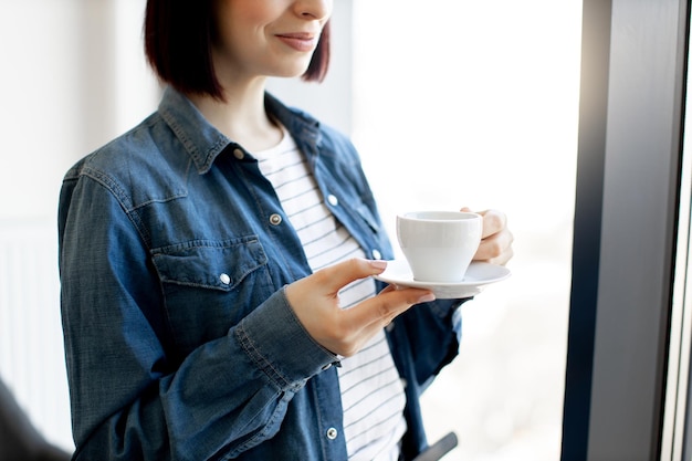 Gros plan d'une femme tenant une tasse de café au bureau