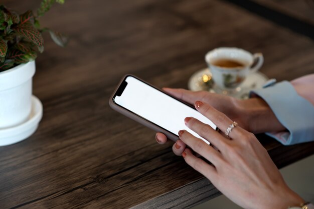 Gros plan d'une femme tenant un téléphone mobile avec écran blanc vierge