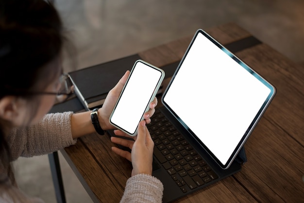 Gros plan d'une femme tenant un téléphone mobile avec écran blanc vierge