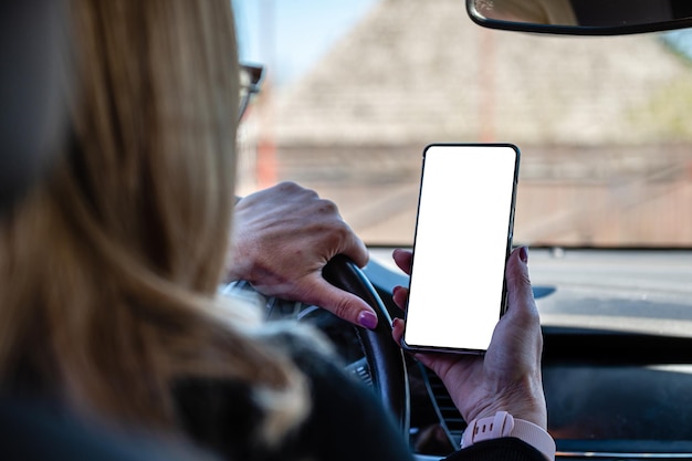 Gros plan d'une femme tenant un téléphone portable à la main avec un écran vide pendant que la voiture conduisait un modèle de maquette