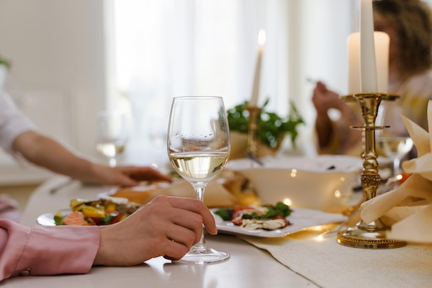 Gros plan d'une femme tenant un verre de vin blanc à la table de fête