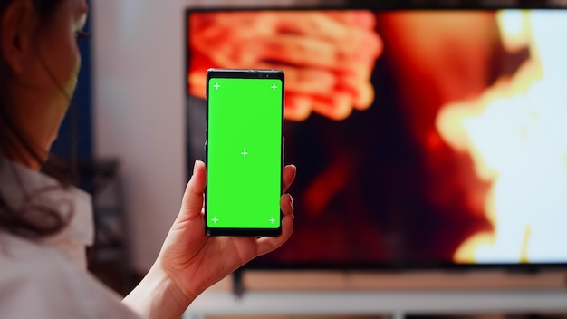 Gros plan d'une femme tenant verticalement un écran vert