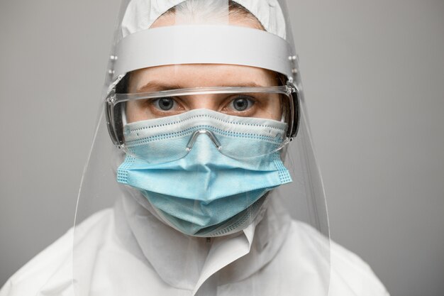 Gros plan de femme en tenue de protection avec bouclier et masque médical.