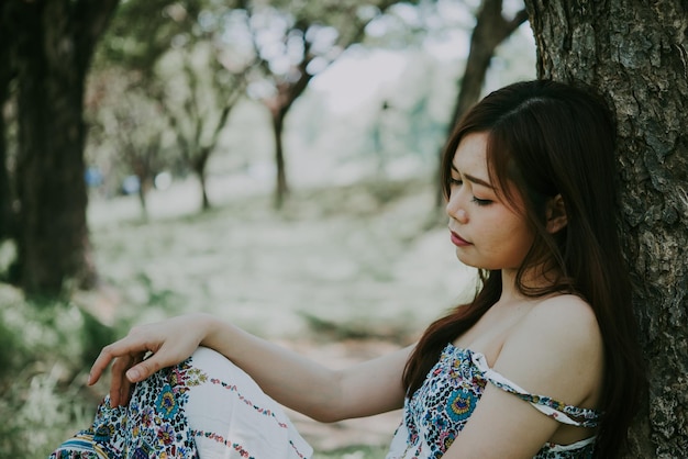 Gros plan femme triste asiatique s'asseoir sous l'arbre concept de fille de style vintage heartbreak