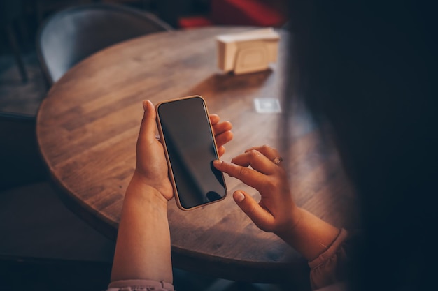 Gros plan sur une femme utilisant un téléphone portable envoyant des massages au café