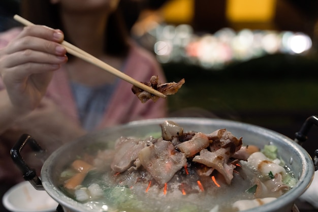 Gros plan des femmes mangeant du porc barbecue sur fond de bokeh