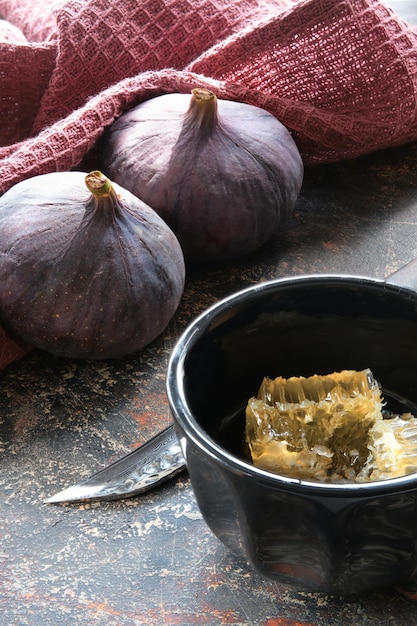 Gros plan sur la figue pourpre d'automne et les plantes sauvages sèches fond brun texturé foncé et torchon de cuisine bordeaux magenta