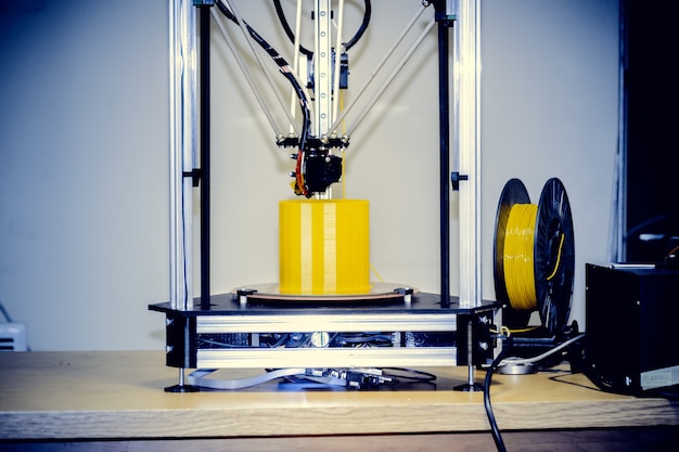 Gros plan de la figure d'impression d'une imprimante 3D moderne. Espace de copie. L'imprimante 3d tridimensionnelle automatique effectue la modélisation des couleurs jaunes en plastique en laboratoire. Technologie additive moderne et progressive. Filtre.