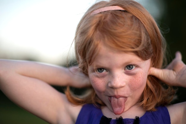 Photo un gros plan d'une fille qui sort sa langue dans le parc.