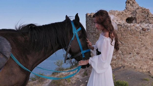 Gros plan Une fille romantique caressant son cheval dans le contexte d'un paysage de montagne Le concept d'équitation Vidéo authentique Vidéo au ralenti 4K