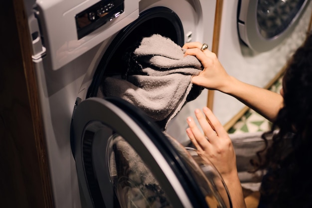 Photo gros plan fille sortant des vêtements de la machine à laver dans une laverie libre-service moderne