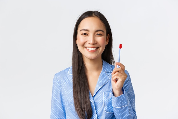 Gros plan sur une fille souriante heureuse montrant des dents blanches après les avoir brossées avec une brosse à dents le matin, debout satisfaite de la nouvelle saveur de dentifrice debout sur fond blanc.