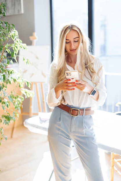 Photo gros plan sur une fille avec un téléphone à la fenêtre dans un bureau lumineux